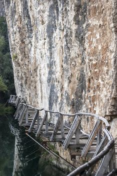 Rock vertical wall wooden path at river