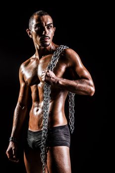 Bodybuilder with chains in dark