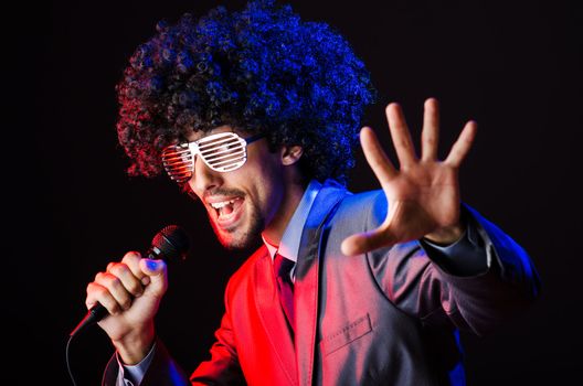 Young singer in afro wig singing at disco