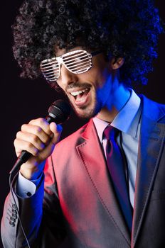 Young singer in afro wig singing at disco