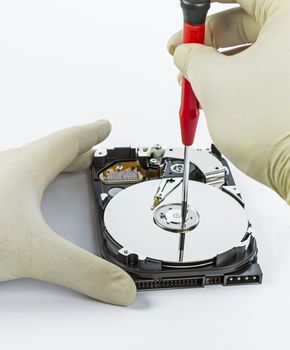technician with open hard-disk and screwdriver in light background