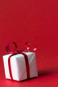 White gift box with red ribbon isolated on red color background