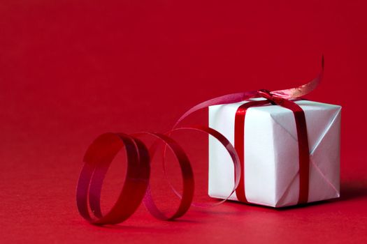 White gift box with red ribbon isolated on red color background