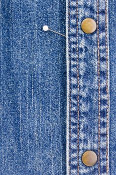 Close-up photograph of a pin on denim material. Add your text to the background.