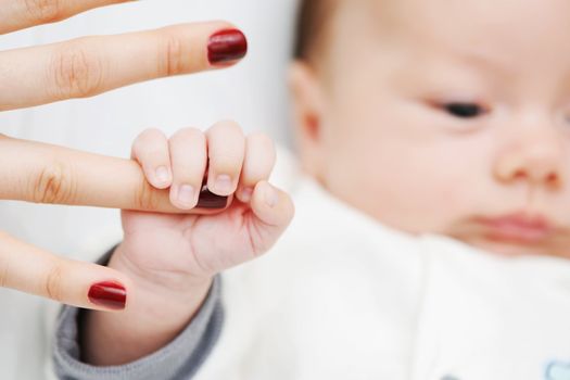 Newborn baby holding mother's finger