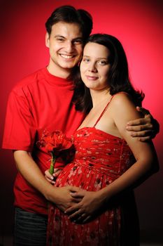Happy pregnant couple over red background