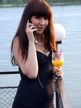 The girl with a cocktail speaks to mobile phone