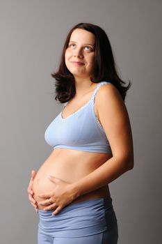 Portrait of a pregnant woman touching her belly with hands