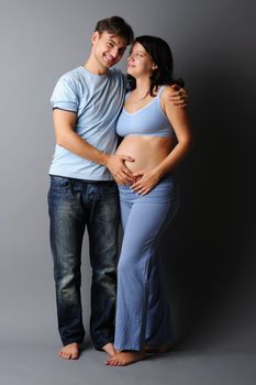 Happy pregnant couple over grey background