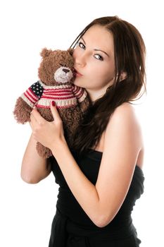 Pretty young woman kissing teddy-bear toy. Isolated on white