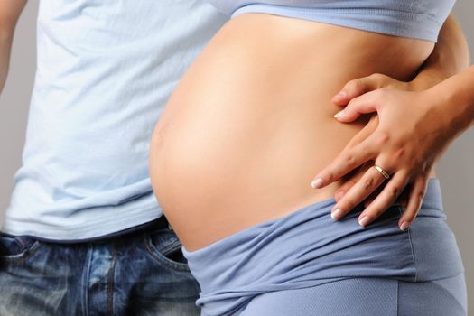 Happy pregnant couple over grey background close-up