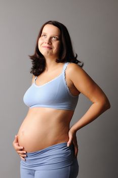 Portrait of a pregnant woman touching her belly with hands