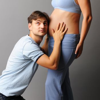 Happy pregnant couple over grey background