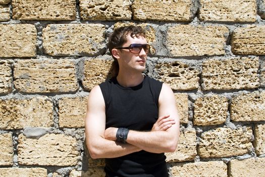 Young man in sunglasses standing near a wall 1