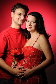 Happy pregnant couple over red background