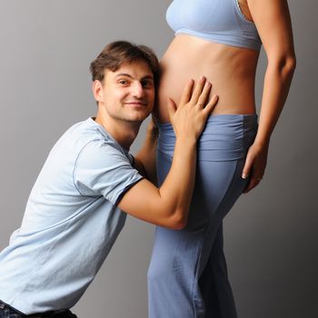 Happy pregnant couple over grey background