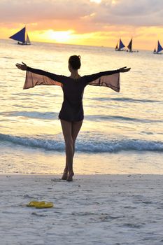 Girl on a beach at sunset with outstretched arms