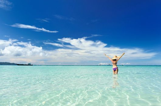 Girl on a tropical beach with outstretched arms