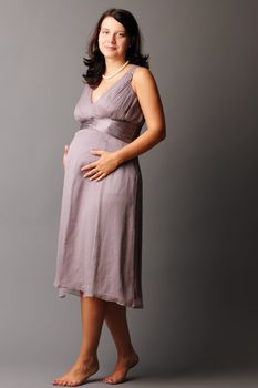 Portrait of a pregnant woman touching her belly with hands