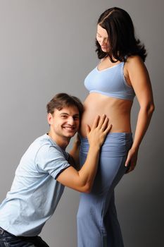 Happy pregnant couple over grey background