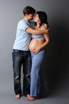 Happy pregnant couple over grey background