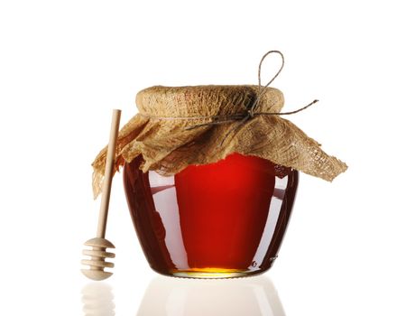 Jar of honey and dipper isolated over white