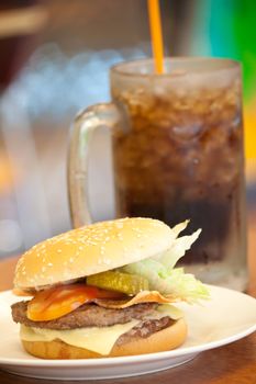 Cheeese beef burger in white plate at a shop with Drinks as background, shallow depth of field