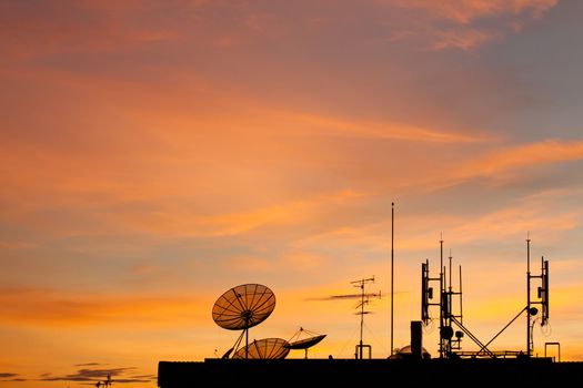 Worldwide Communication,  Satellite and other antenna network against beautiful sky at sunset, silhouette style