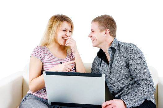 young couple laughing while sitting on the couch with a laptop