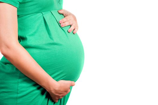 Belly of a pregnant girl in green dress. Isolated