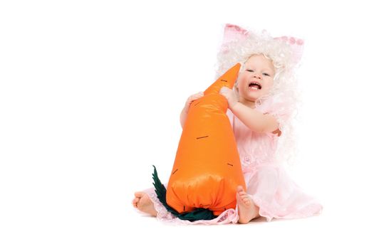 Happy baby girl plays with a carrot. Isolated