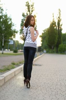 Sexy playful young woman walking on the sidewalk