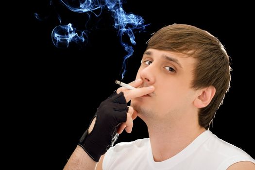 Young man smoking a cigarette. Isolated on black