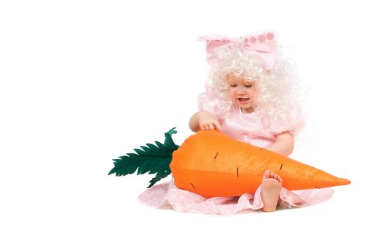 Funny baby girl plays with a carrot