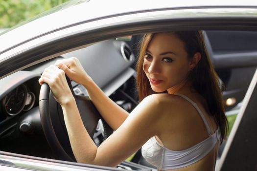 Young woman in lingerie behind the wheel of a car
