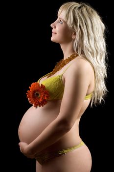 Pregnant young blonde with red flower. Isolated on black