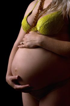 Belly of a young pregnant woman. Isolated on black
