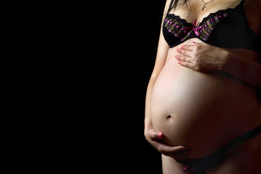 Belly of a pregnant woman. Isolated on black