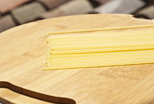 spaghetti pasta on wooden board with roof in the background.