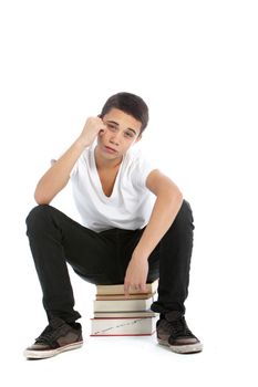Dejected teenaged boy sitting on top of a pile of his textbooks with a despondent expression isolated on white