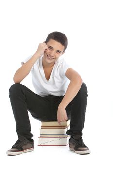 Happy teenage student sitting on a stack of his textbooks grinning with pleasure isolated on white