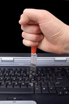 Hand with a knife in the laptop keyboard