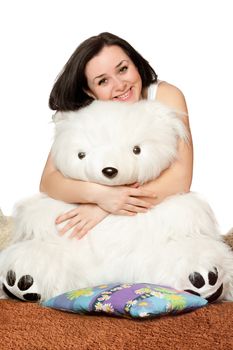 Smiling girl sitting in an embrace with a large teddy bear