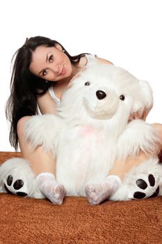 Lovely girl sitting in an embrace with a large teddy bear