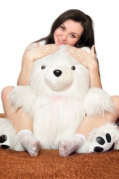 Beautiful girl sitting in an embrace with a large teddy bear