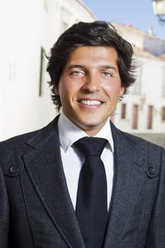 View of a happy business man with a black suitcase on a European city.