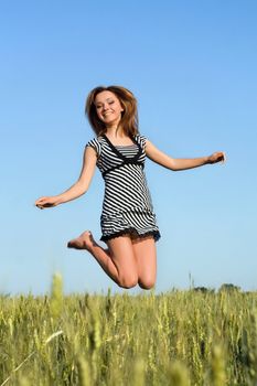Happy attractive girl jumping in field