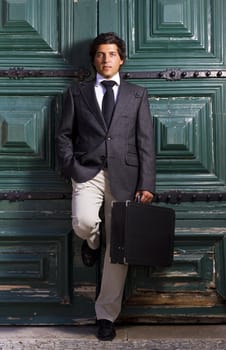 View of a happy business man with a black suitcase on a European city.