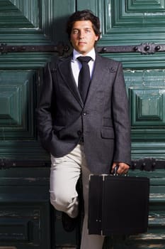 View of a happy business man with a black suitcase on a European city.
