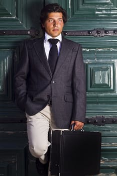 View of a happy business man with a black suitcase on a European city.